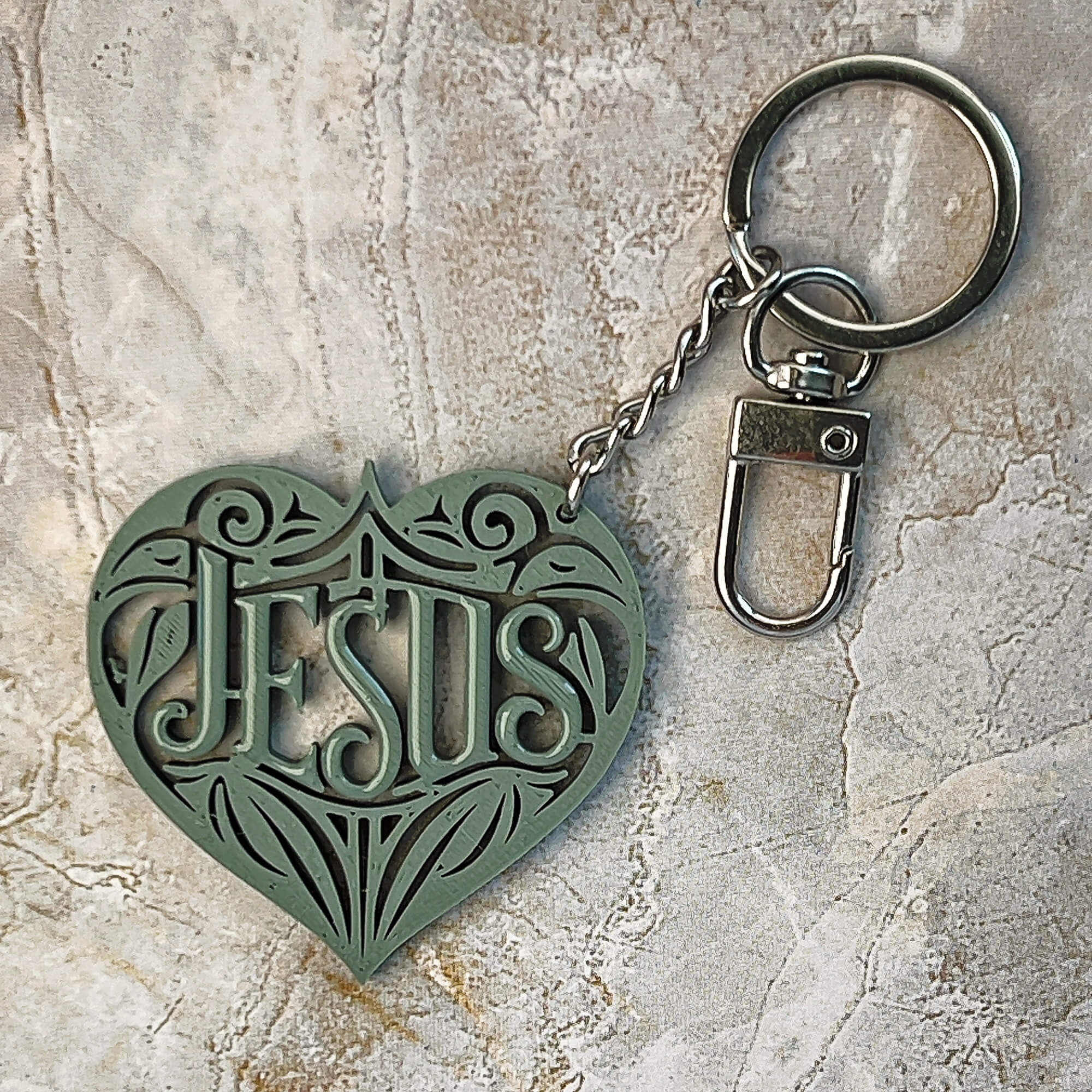 Sage green, heart-shaped keychain with 'Jesus' engraving 